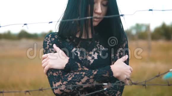 女孩黑发难民背后铁丝网营地慢动作视频自由的概念令人不安女人的手和铁丝网视频的预览图