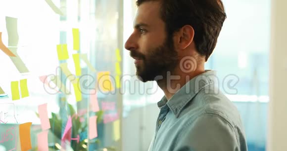 男性高管看着玻璃上粘粘的纸条视频的预览图