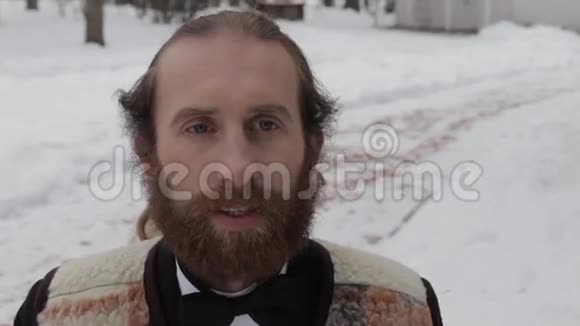 穿着西装戴着领结的长胡子男人在冬天的背景下视频的预览图