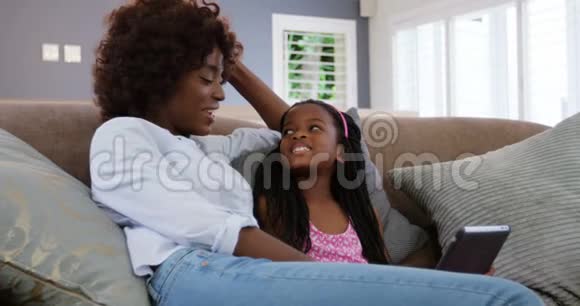 母女俩坐在沙发上用数码平板电脑视频的预览图