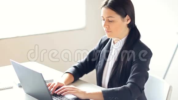 在办公室用笔记本电脑工作的女商人视频的预览图