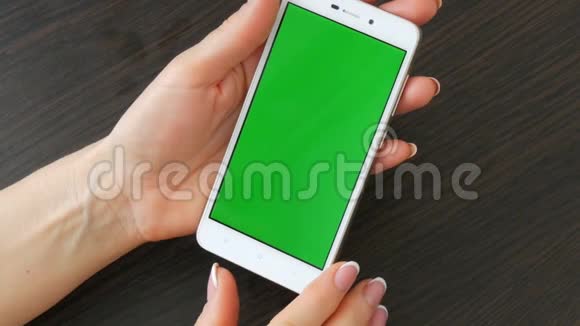 女性手与美丽的法国美甲采取白色智能手机与绿色屏幕使用智能手机手持视频的预览图