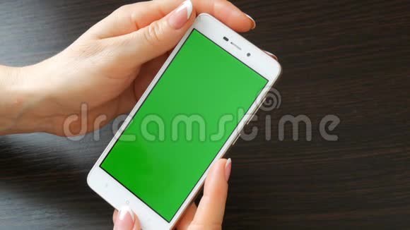 女性手与美丽的法国美甲采取白色智能手机与绿色屏幕使用智能手机手持视频的预览图