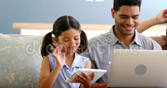 使用笔记本电脑手机和数码平板电脑的幸福家庭视频的预览图
