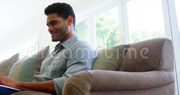 客厅里的快乐男人用笔记本电脑视频的预览图