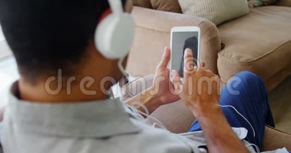 客厅里的快乐男人在听手机音乐视频的预览图