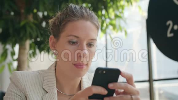 一位年轻女士在咖啡厅里用智能手机视频的预览图