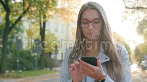 一位年轻女士走路和使用智能手机视频的预览图