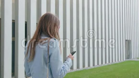 一位年轻女士走路和使用智能手机视频的预览图