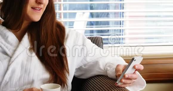 女人一边喝咖啡一边用手机视频的预览图