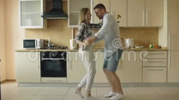 有魅力的年轻快乐的一对夫妇在家厨房做饭的时候尽情地跳舞视频的预览图