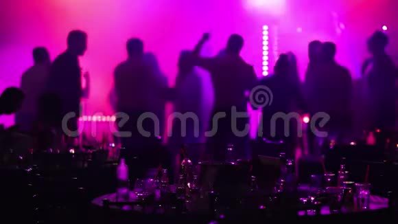 在餐馆或夜总会举行的青年聚会在剪影的背景下摆满酒和食物的宴会桌视频的预览图