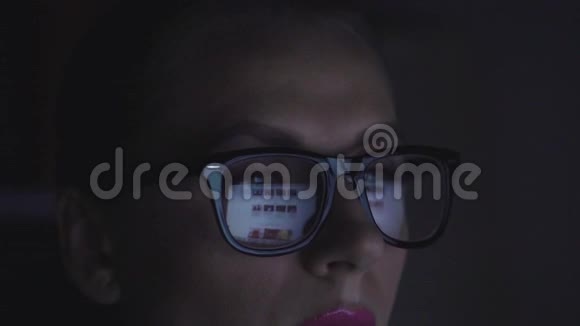 戴眼镜的女人看着监视器上网视频的预览图