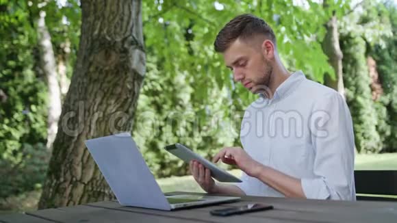 一个年轻人用笔记本电脑和平板电脑视频的预览图