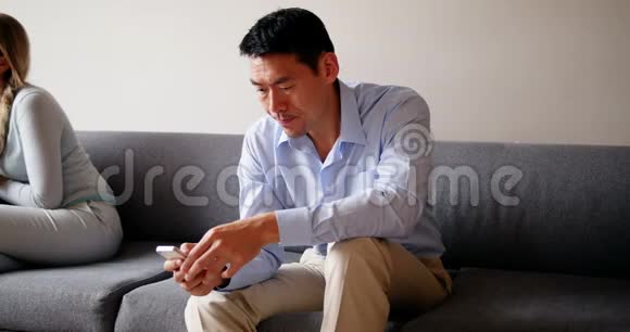 男人坐在沙发上用手机视频的预览图