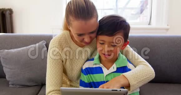 母亲和儿子在客厅里使用数码平板电脑视频的预览图