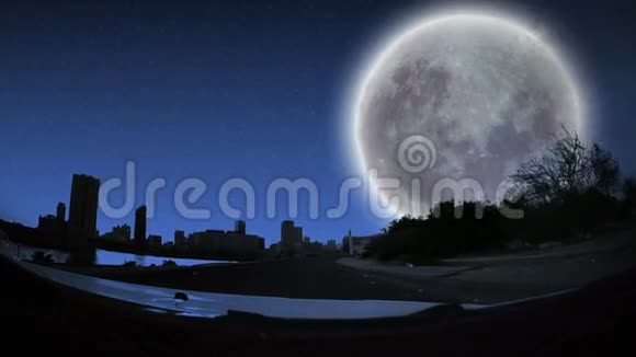 晴朗的夜晚和满月从汽车前穿过城市视频的预览图