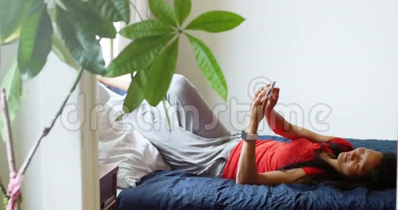 女人在卧室里用手机视频的预览图