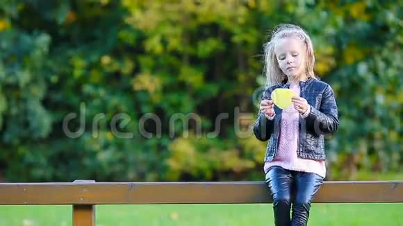 可爱的小女孩在美丽的秋天公园户外有黄色的枫叶视频的预览图