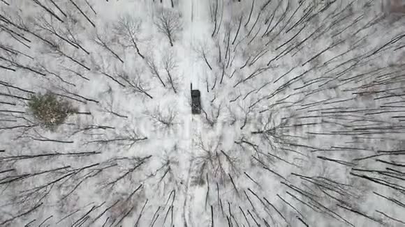 在白雪覆盖的森林中乘坐冬季道路的6x6越野车的空中景观视频的预览图