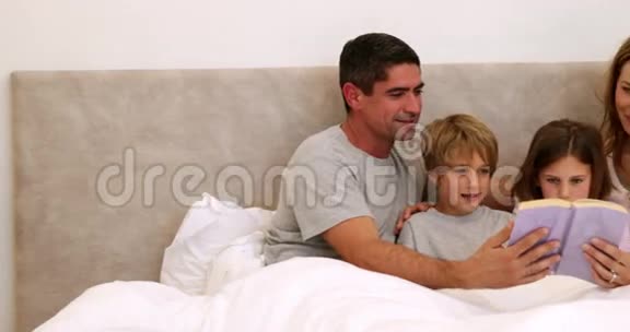 快乐的父母和孩子一起在床上读书视频的预览图