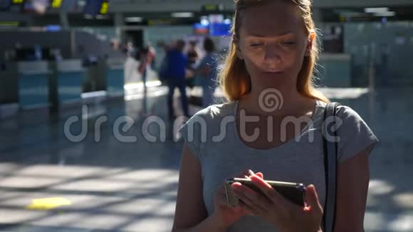 女士在机场候机室使用智能手机对机场飞行的期望4k慢动作视频的预览图