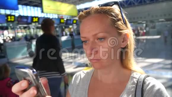 女士在机场候机室使用智能手机对机场飞行的期望4k慢动作视频的预览图