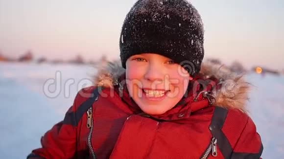 在夕阳的背景下冬天公园里的一个孩子微笑视频的预览图