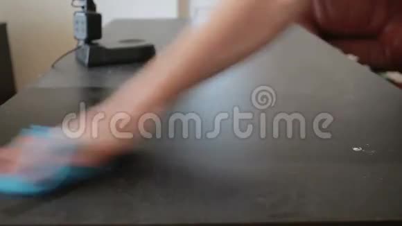手拿着一块蓝色的抹布擦去桌子上的灰尘视频的预览图
