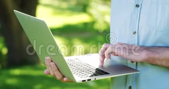 阳光明媚的一天男人在公园里用笔记本电脑视频的预览图