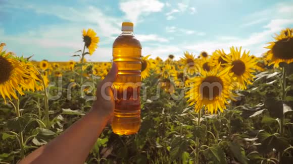 农夫手里拿着一瓶塑料生活方式的葵花籽油在他的手里的阳光下慢动作视频蓝天视频的预览图