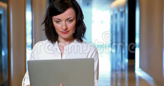 女高管在走廊里用笔记本电脑视频的预览图