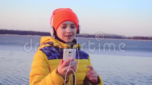 年轻女孩带着手机在耳机上听音乐女孩带着耳机随着音乐跳舞视频的预览图