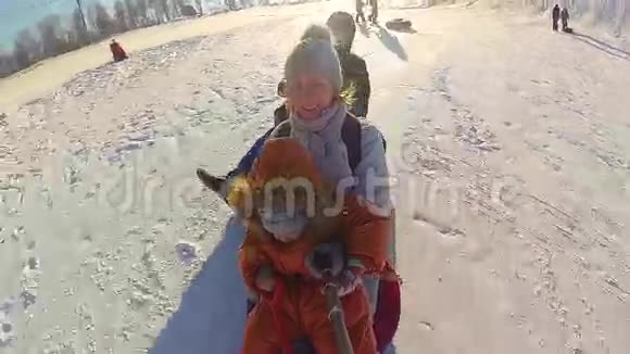 幸福的家庭乘坐和微笑的雪管在雪道上慢动作冬天的雪景户外运动视频的预览图