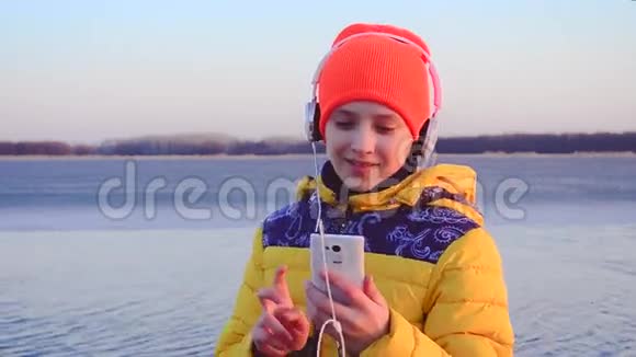 女孩戴着耳机随着音乐跳舞微笑的女孩带着耳机听音乐视频的预览图