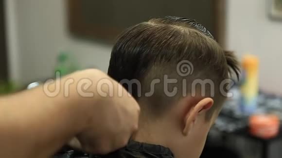 小男孩坐在理发店的椅子上被理发师理发视频的预览图