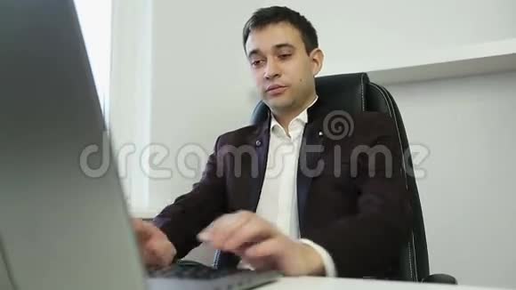 年轻的商人在办公室里用笔记本电脑工作视频的预览图