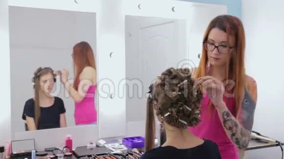 理发师为年轻漂亮的女人做发型用喷发剂视频的预览图
