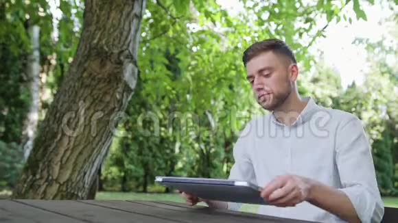 一个年轻人在公园里用笔记本电脑视频的预览图