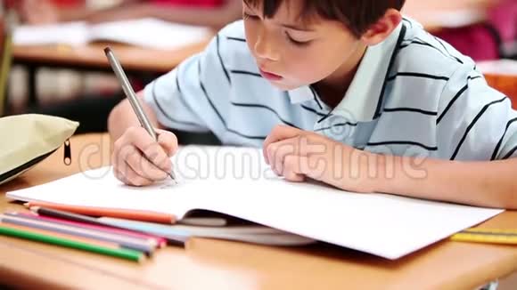 微笑的男孩在笔记本上写字视频的预览图