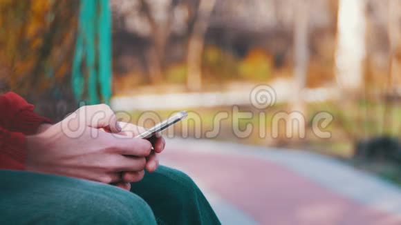 在城市公园的长椅上使用智能手机的年轻人视频的预览图