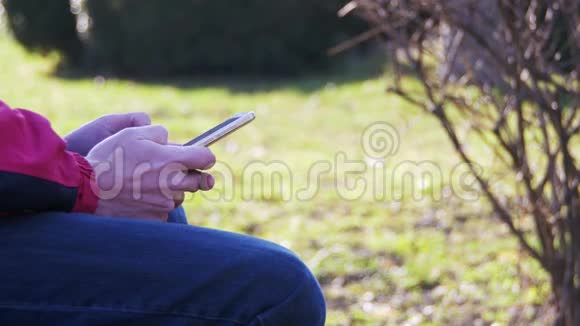 在城市公园的长凳上用手机的年轻人视频的预览图