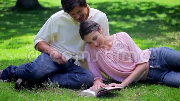 快乐的一对夫妇坐在草地上看书视频的预览图