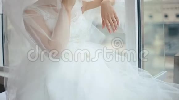 迷人的金发新娘穿着白色礼服在咖啡馆的窗户附近摆姿势视频的预览图