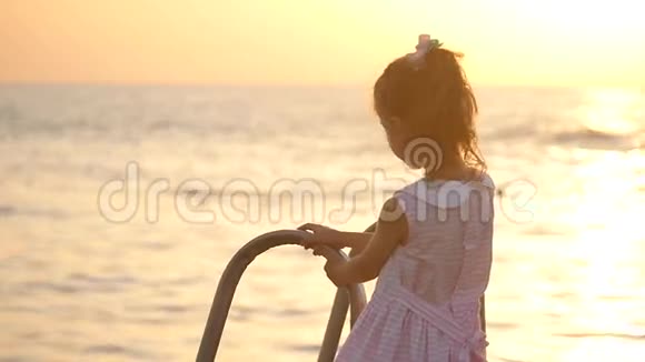 日落时海边美丽的小女孩视频的预览图