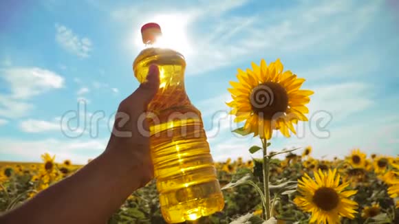 农夫手里拿着一瓶塑料葵花籽油阳光洒在他的手里慢动作视频蓝天背景视频的预览图