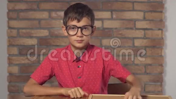 坐在办公桌前的孩子拿着一张挂图上面写着红色的砖墙视频的预览图