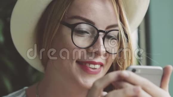 女人在咖啡馆里用智能手机购物漂亮的年轻女性使用手机视频的预览图
