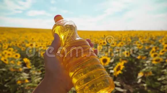 农夫手里拿着一瓶塑料葵花籽油在阳光下生活慢动作视频蓝天视频的预览图