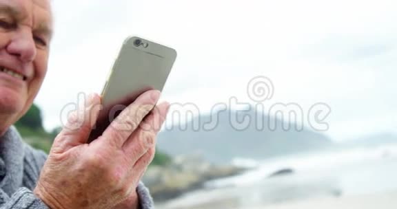 在海滩上使用手机的老人视频的预览图